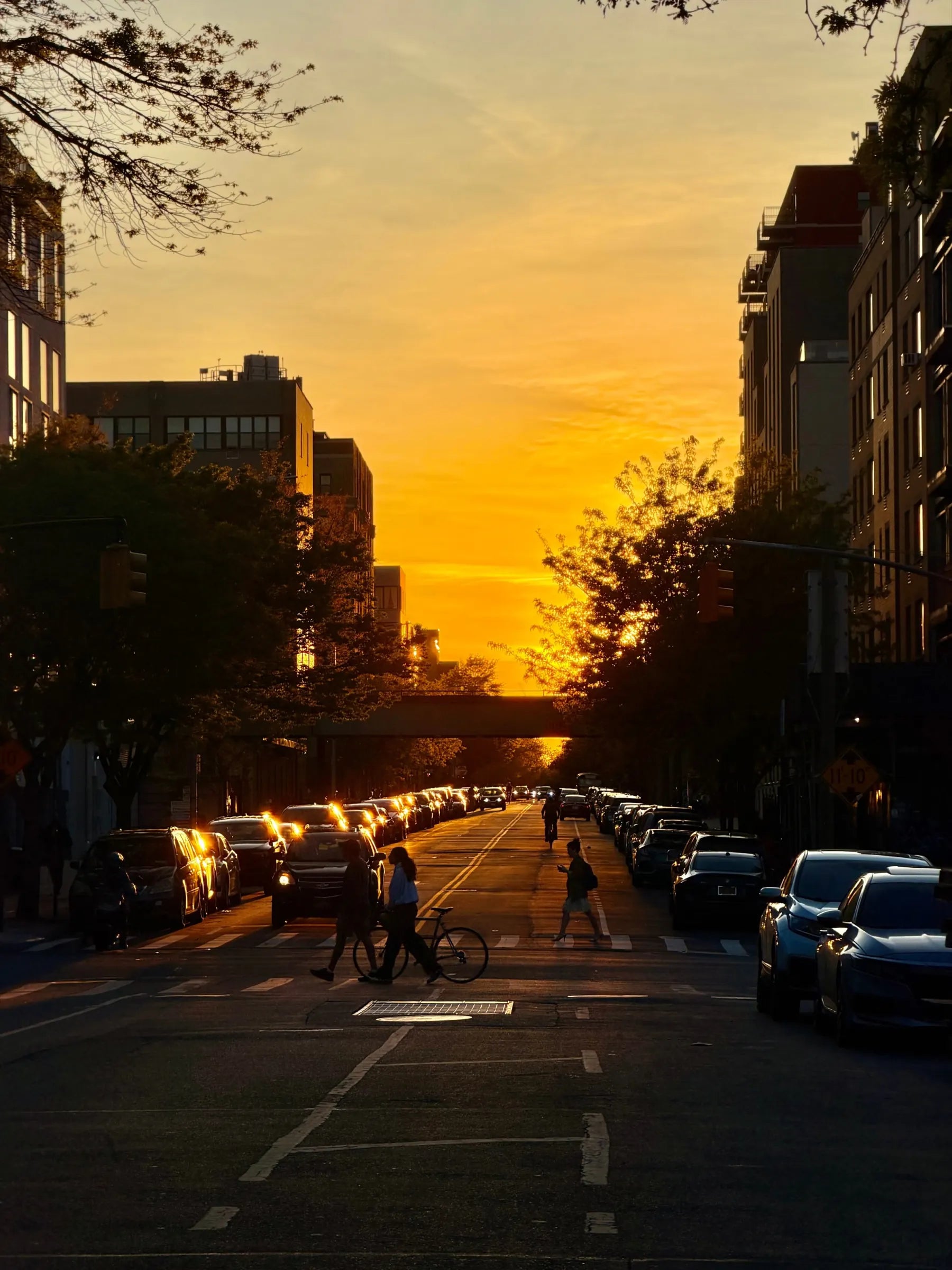 People crossing a New York street beneath a golden sunset
